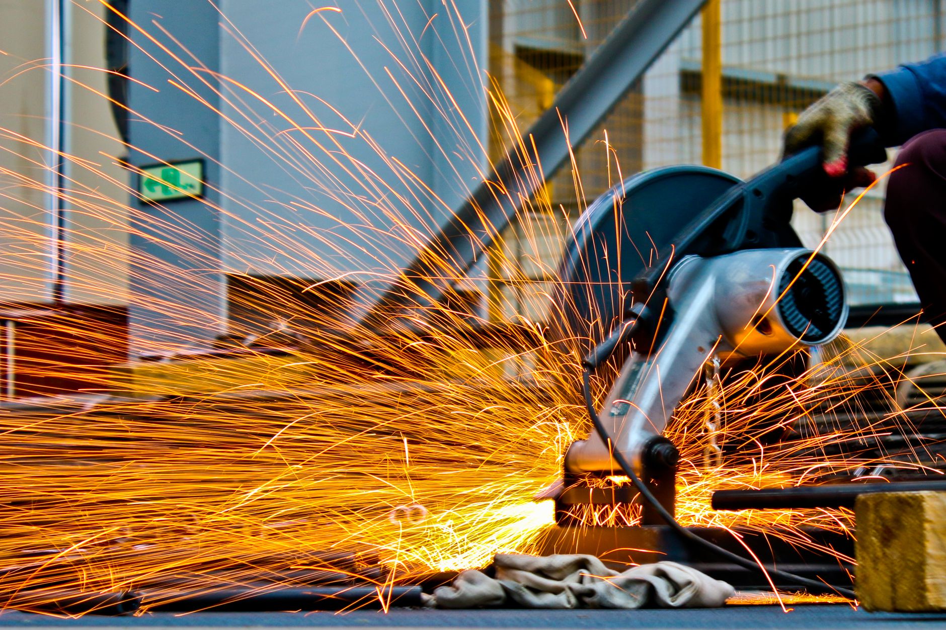 Angle grinder with a thin cut-off wheel making a straight cut through steel bar, sparks trailing