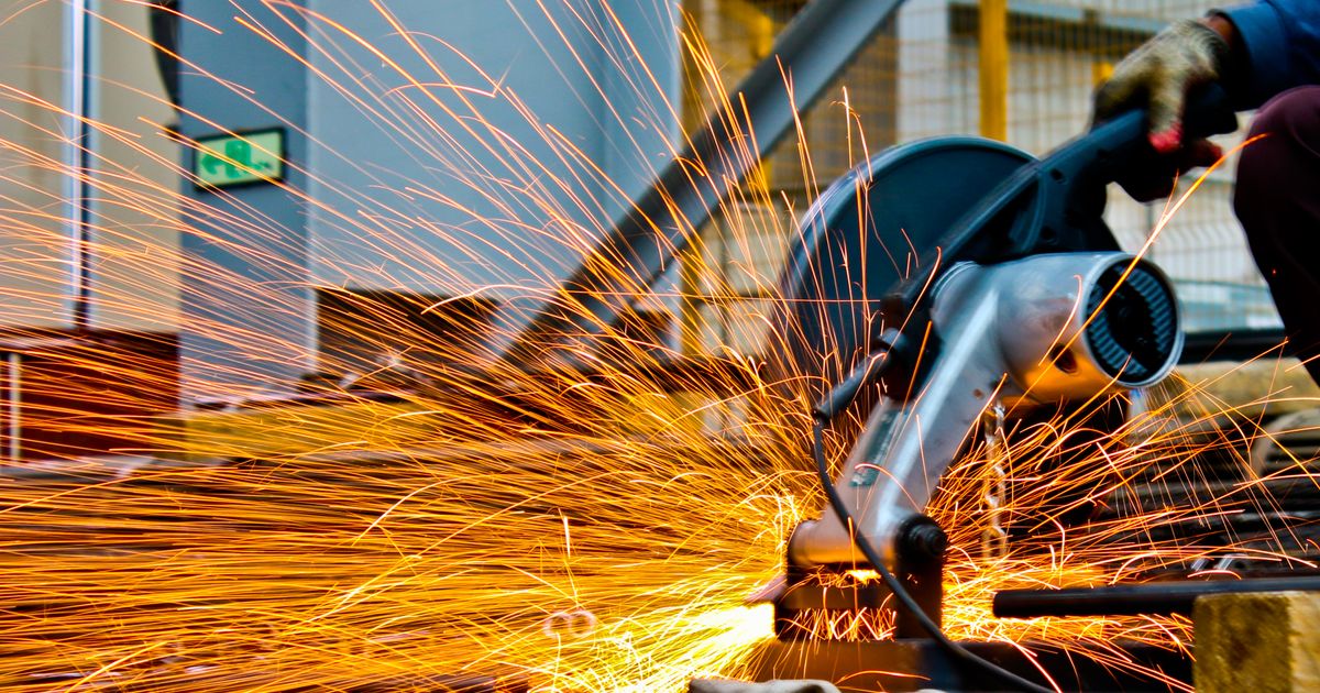 A worker cutting metal with an angle grinder as sparks fly — cut-off wheel rpm and thickness, Whitby Abrasives, Ontario, Canada
