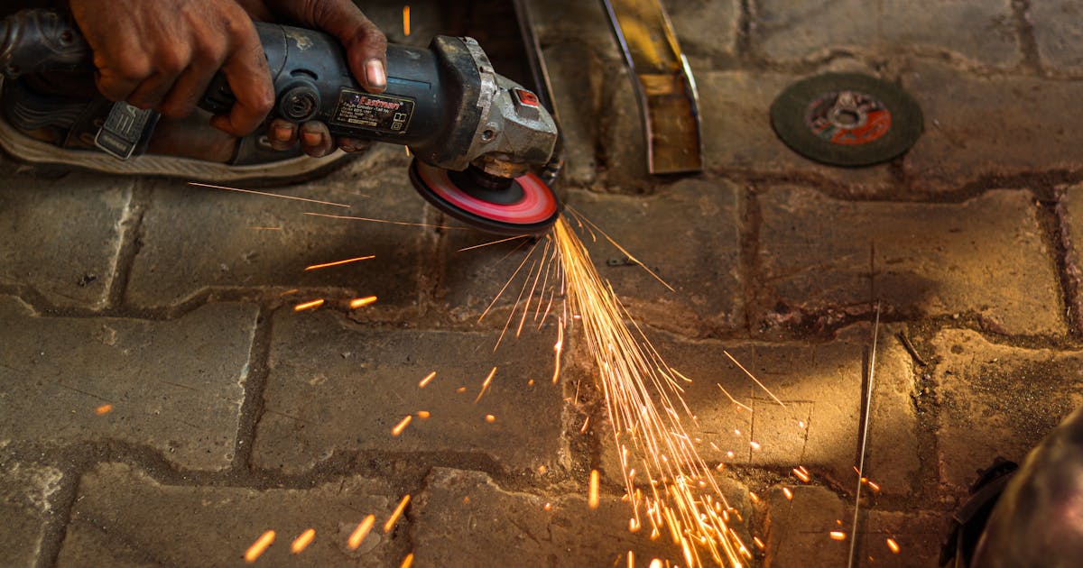 Worker grinding steel for heavy stock removal — Whitby Abrasives grinding wheels, Ontario