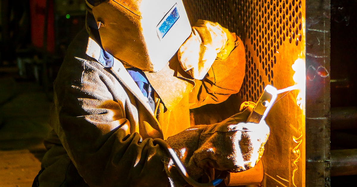 Welder in full protective equipment with sparks — abrasive safety and compliance, Ontario