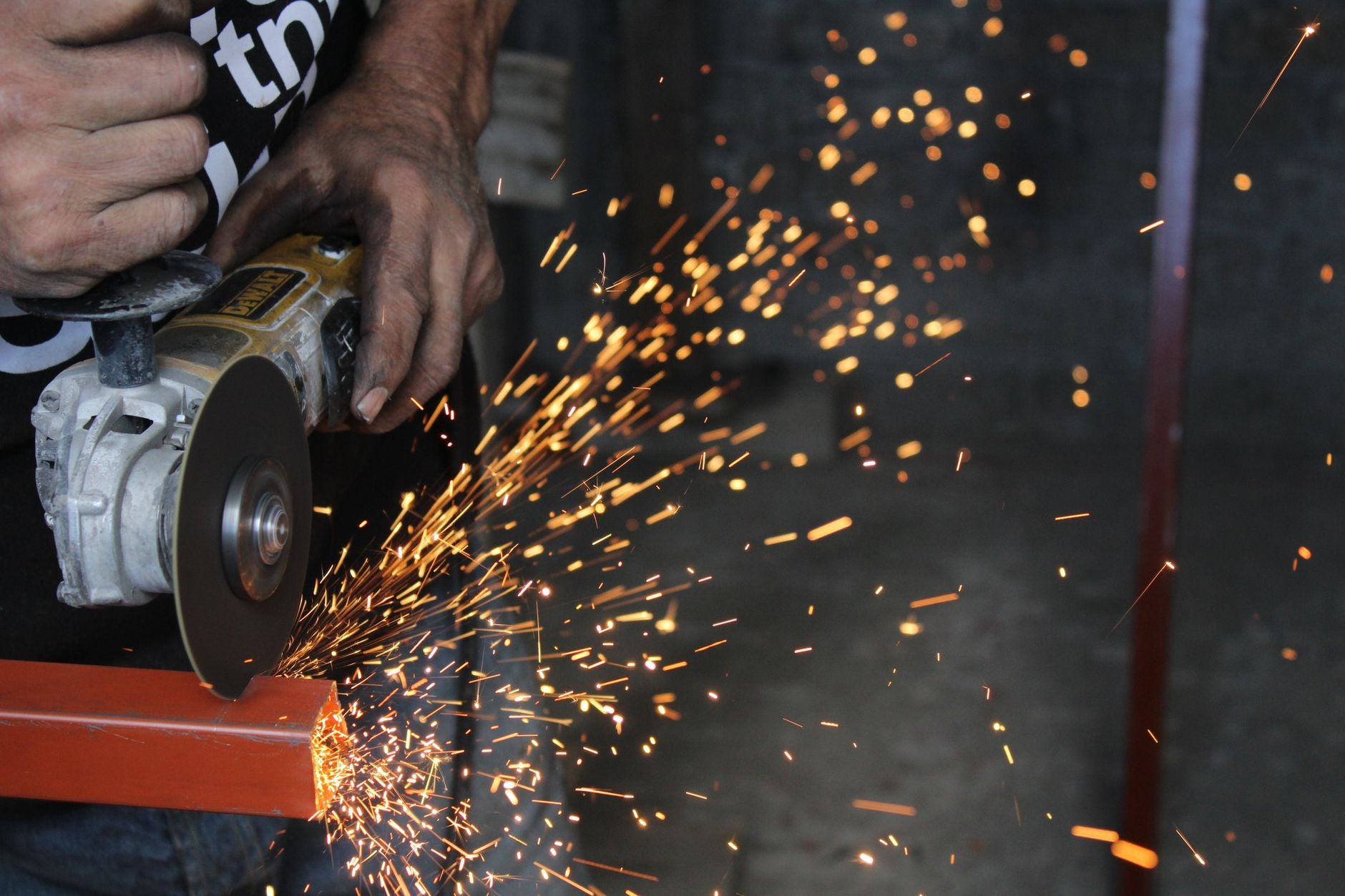 Angle grinder making a straight 90-degree cut in steel with a thin cutting disc, sparks trailing off the edge of the wheel