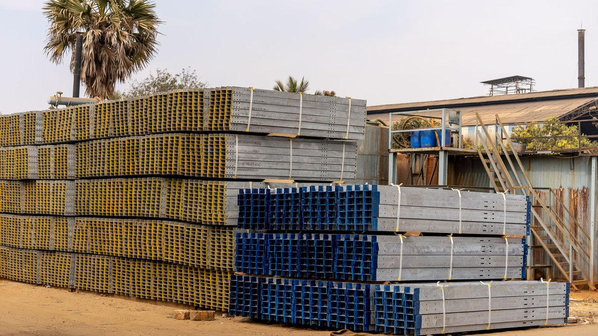 Stacks of steel beams and coils stored in an industrial warehouse yard