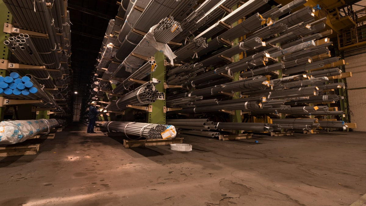 Stacks of steel bar and sheet stock in an industrial warehouse ready for fabrication