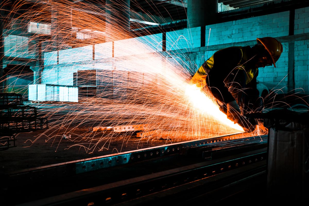 Worker cutting steel with an angle grinder throwing sparks — comparing abrasive brands in Canada