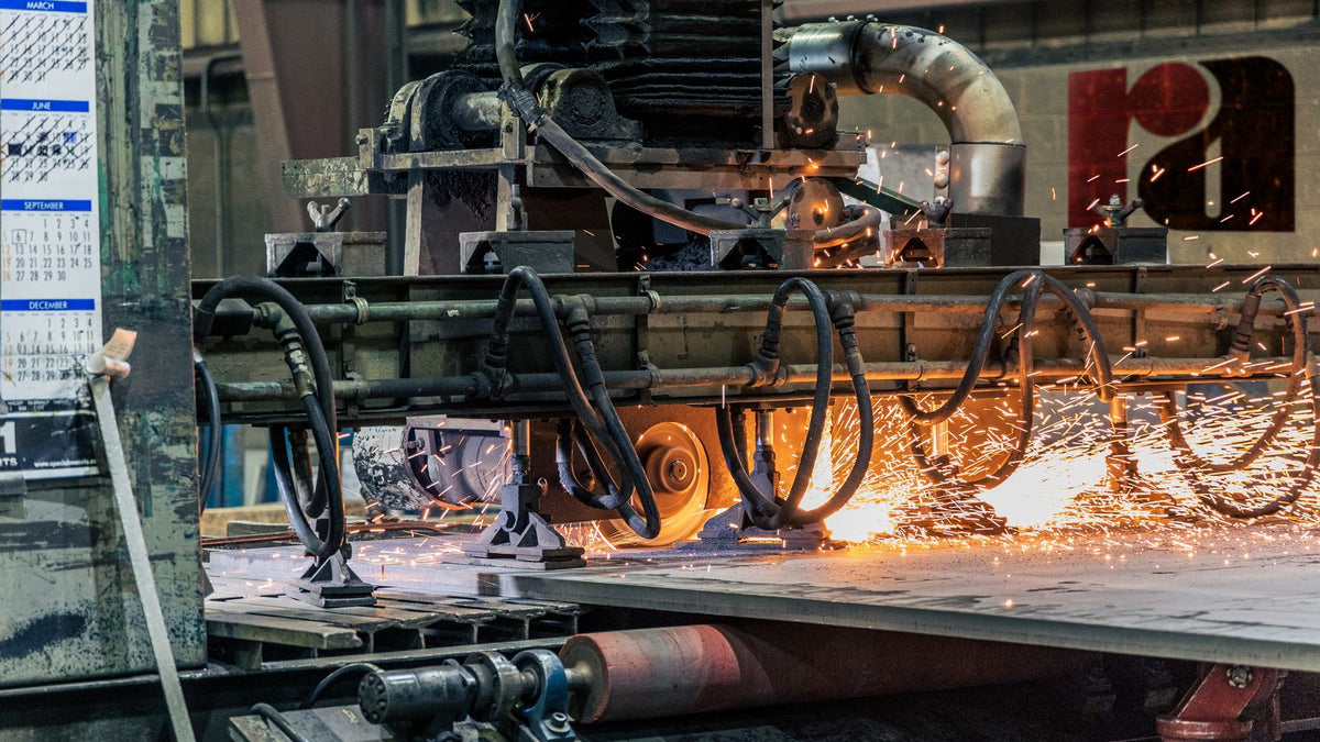 A fabricator using a cutting tool on a thick steel plate in an industrial shop