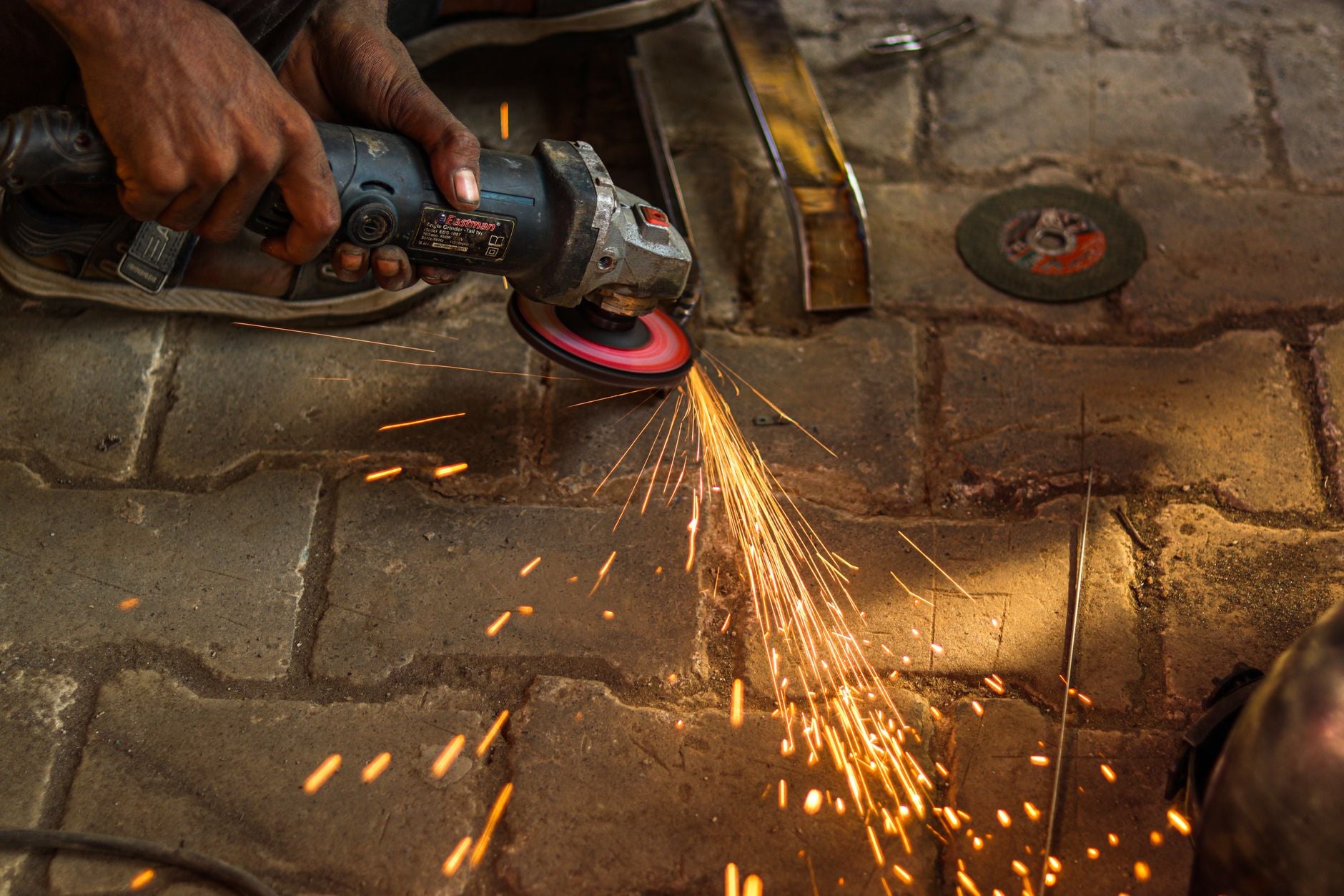 Angle grinder spindle with flange nut and abrasive disc, showing the threaded arbor mount
