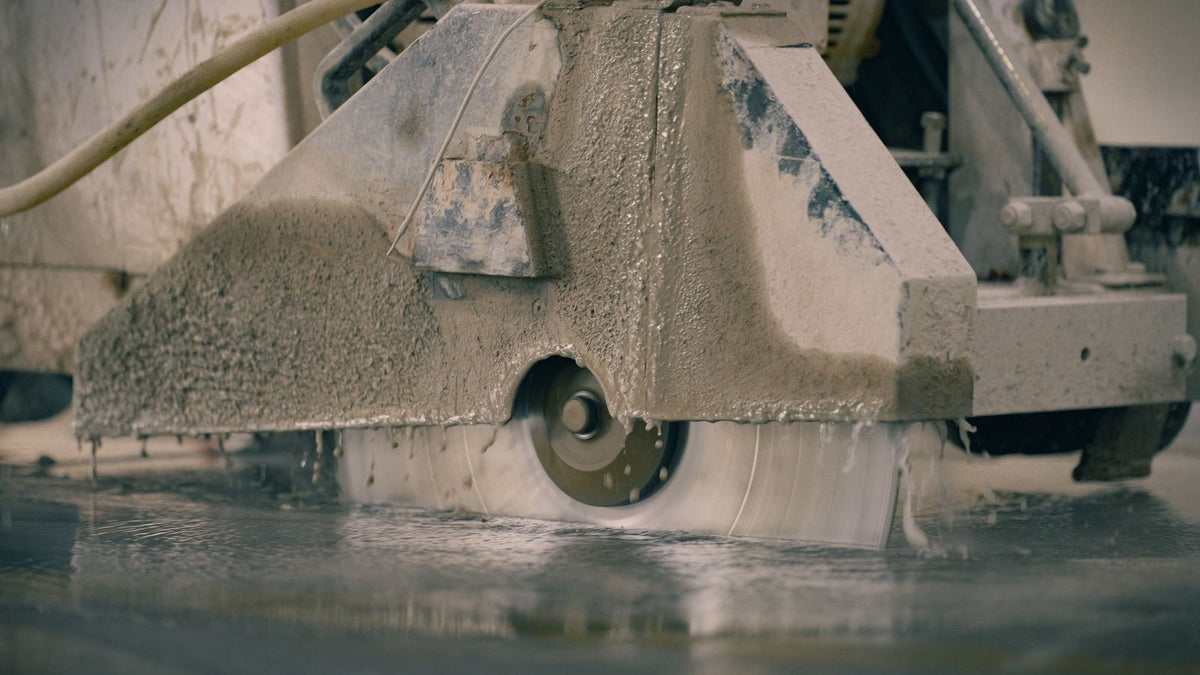 Construction worker cutting a concrete block with a handheld saw on a residential building site.