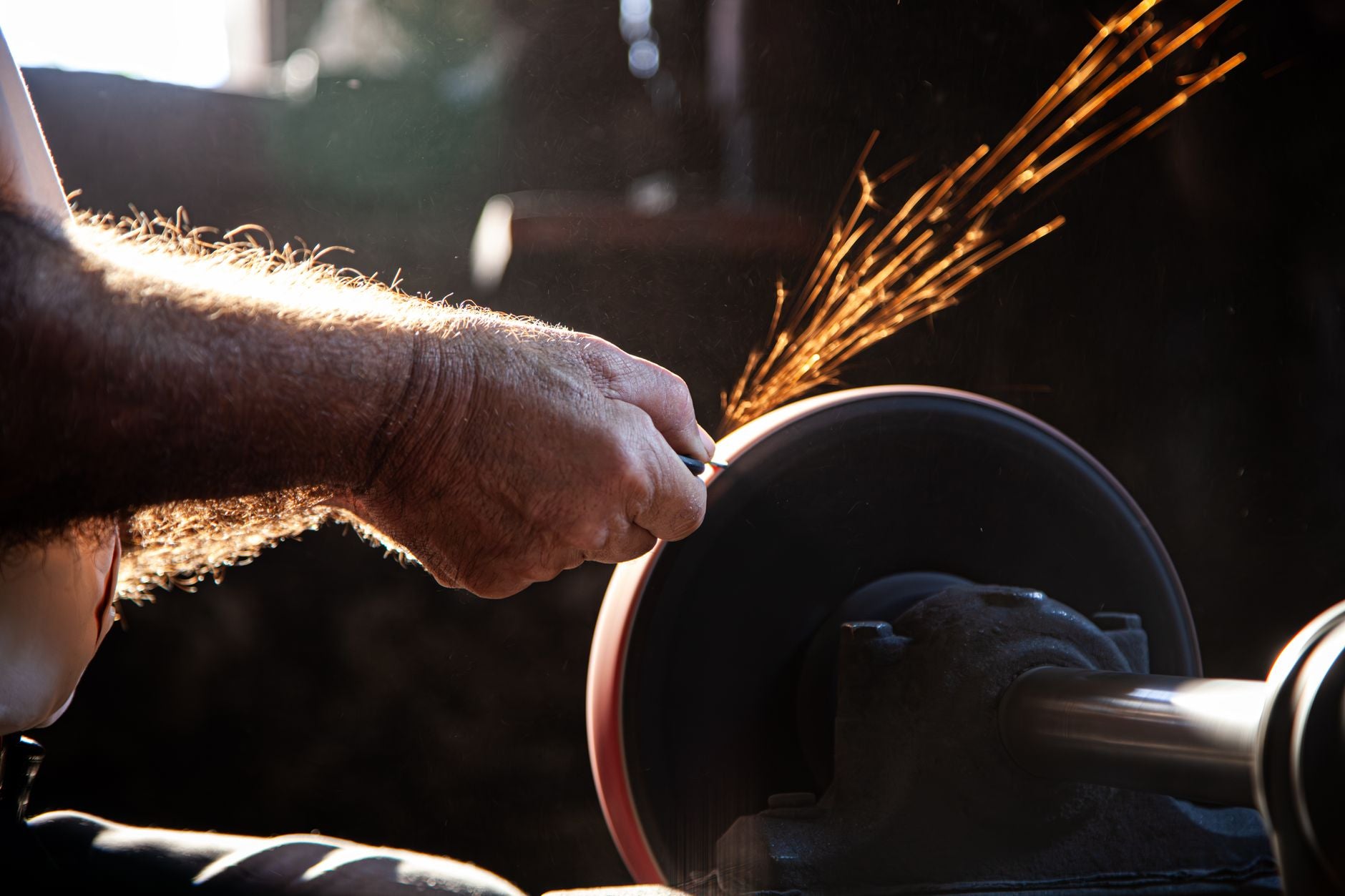 Operator dressing a vitrified bench grinder wheel with the dresser supported on the tool rest