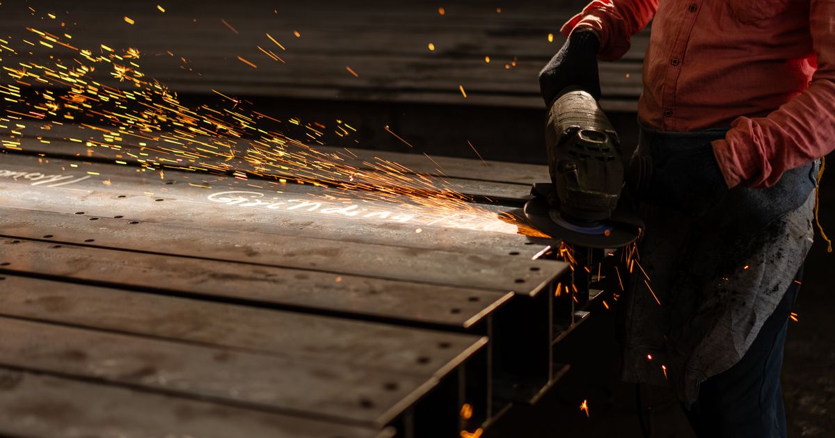 A worker grinding a metal beam with an angle grinder, sparks flying — how to prevent grinding burn, Whitby Abrasives, Ontario, Canada