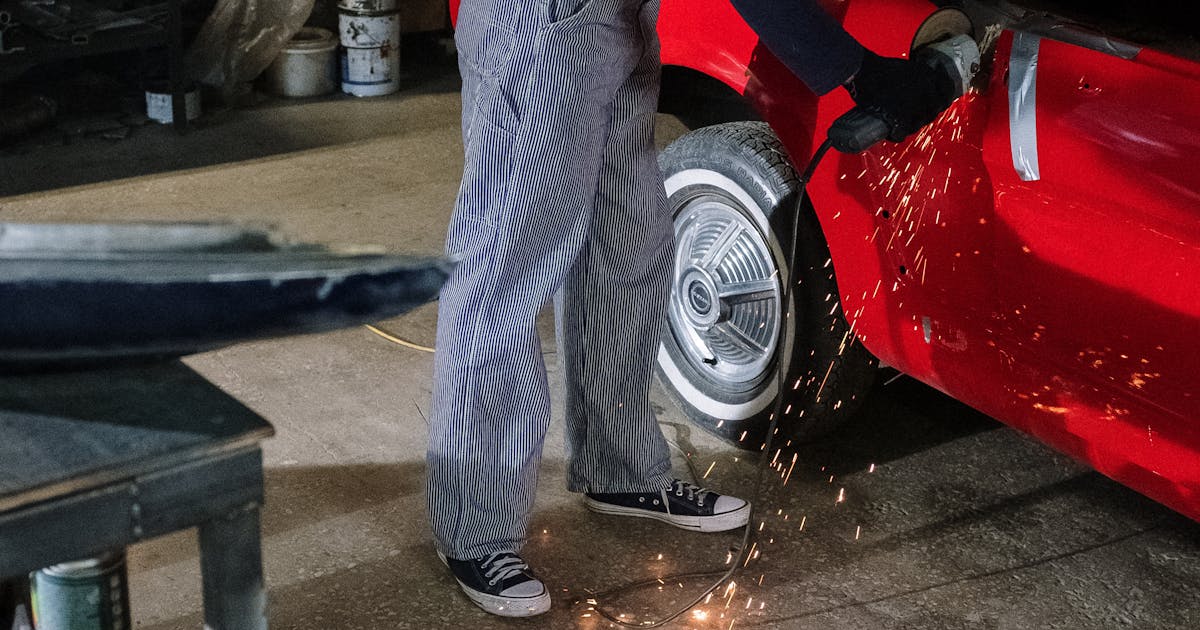 Auto body technician grinding a car panel with sparks — automotive abrasives, Ontario