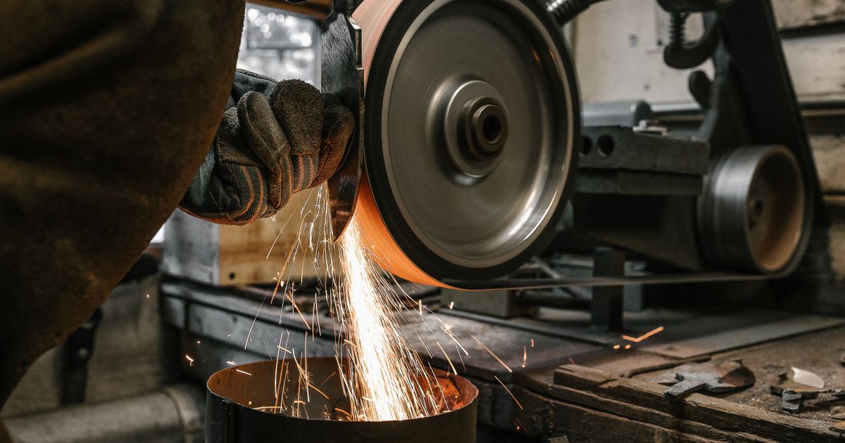 Close-up of a metalworker grinding a steel blade with sparks — fiber disc backing pad, Whitby Abrasives, Ontario, Canada