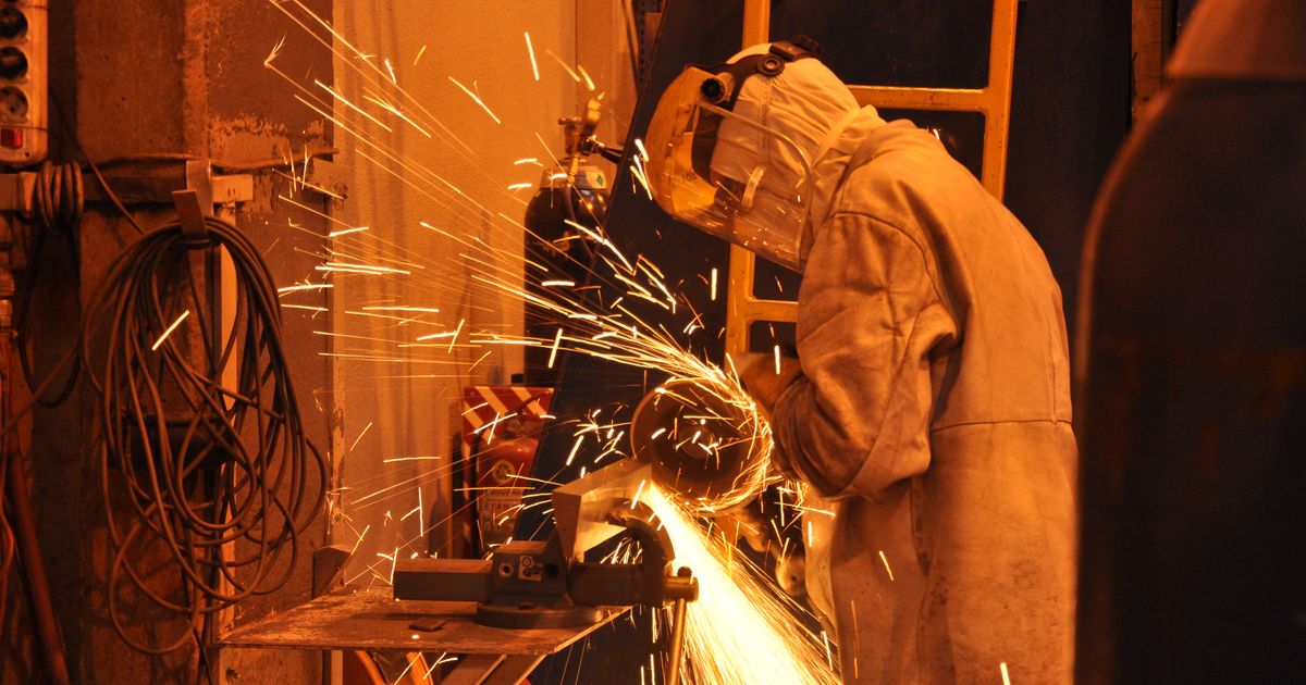 A worker in protective gear grinding metal with sparks in an industrial shop — abrasive disc shelf life, Whitby Abrasives, Ontario, Canada