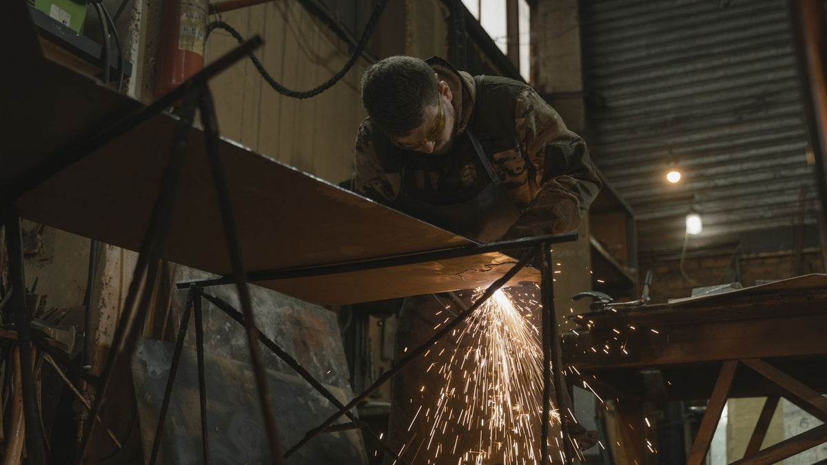 Fabricator grinding a steel weld seam in a metal fabrication shop, sparks flying