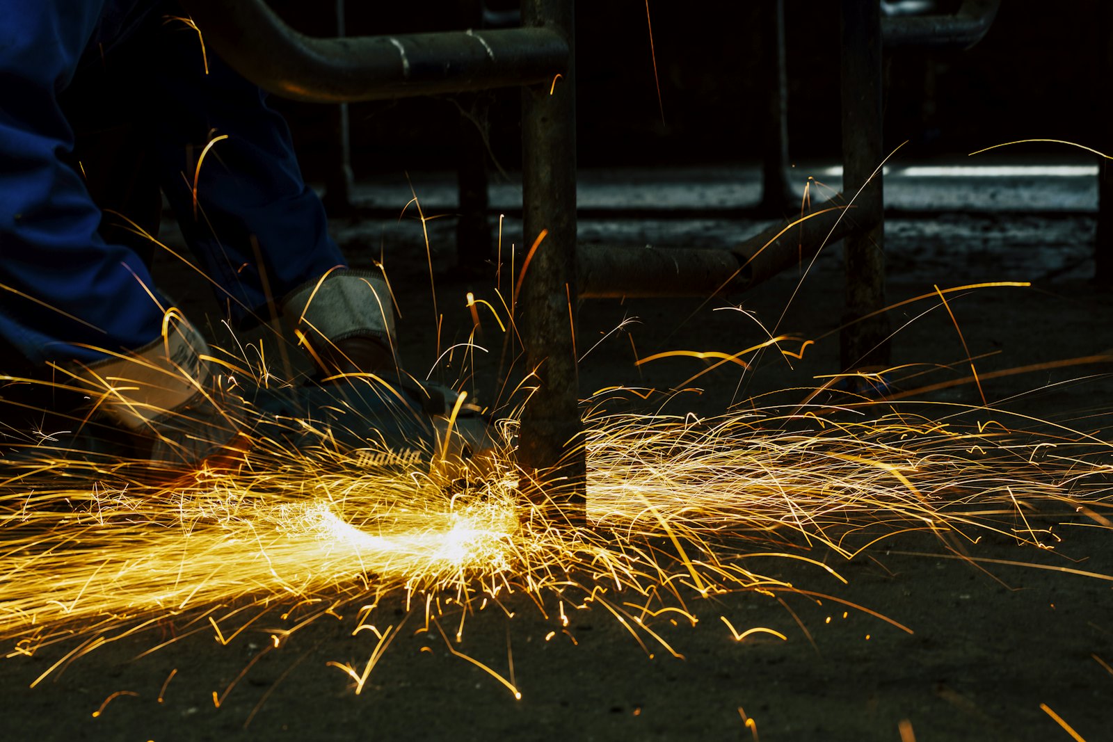 Tradesperson cutting metal with an angle grinder, sparks flying