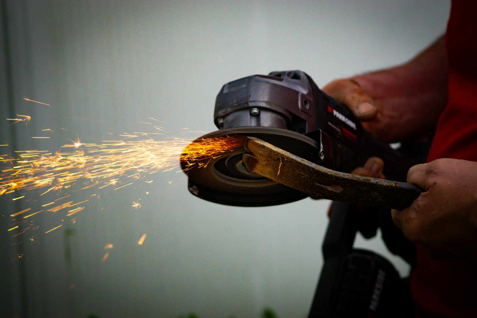 Tradesperson using an angle grinder on metal with sparks flying